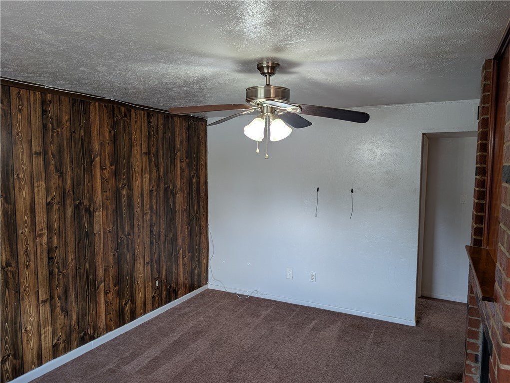 2901 Minnesota Avenue Bryan, TX 77803 - Photo 6 of 16 Empty room with a textured ceiling, dark colored carpet, wooden walls, and ceiling fan