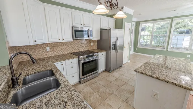 a kitchen with stainless steel appliances granite countertop a stove a sink dishwasher a refrigerator and white cabinets with wooden floor