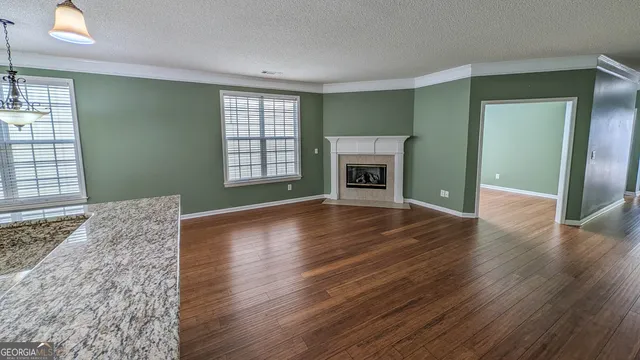 an empty room with wooden floor fireplace and windows