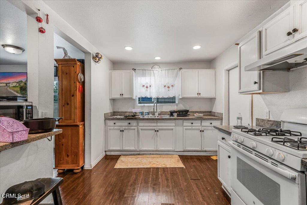 970 Laurel Street West Oxnard, CA 93033 - Photo 5 of 40 a kitchen with granite countertop appliances cabinets and a wooden floor
