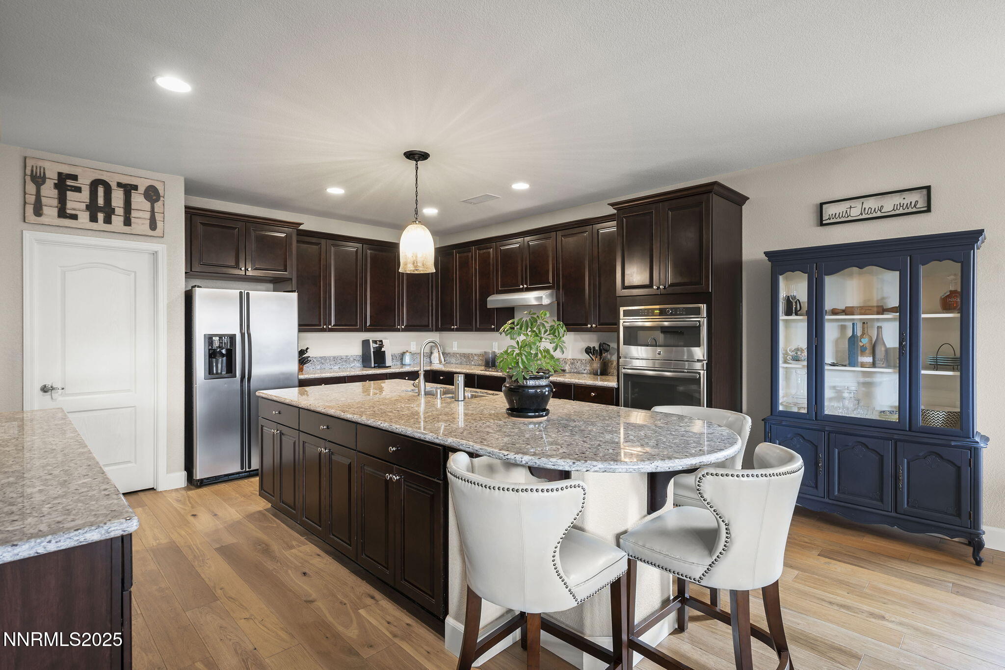 2835 Tobiano Drive Reno, NV 89521 - Photo 10 of 33 a large kitchen with granite countertop a dining table chairs wooden floor cabinets and stainless steel appliances