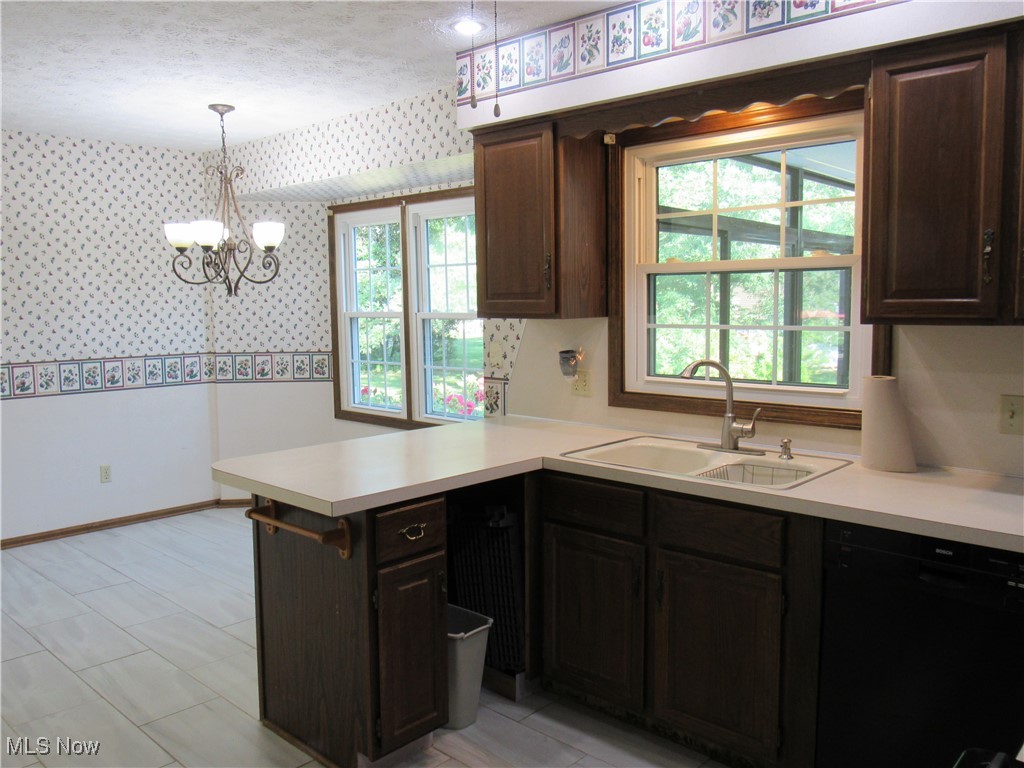 1120 Vincent Road Southeast North Canton, OH 44720 - Photo 18 of 50 Kitchen featuring a notable chandelier, kitchen peninsula, dinette area, black dishwasher, dark brown cabinetry, and sink