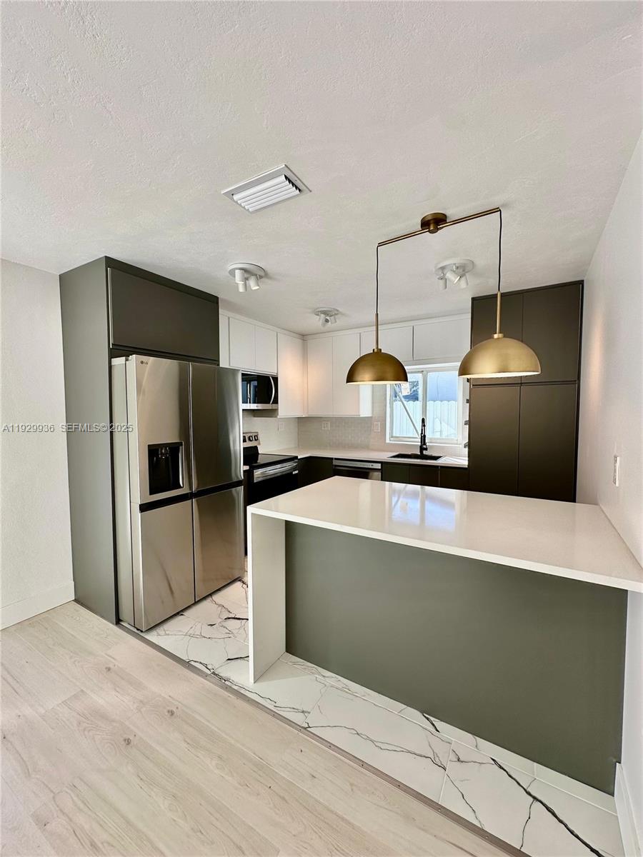 629 Southwest 4th Street Hallandale Beach, FL 33009 - Photo 7 of 27 a kitchen with stainless steel appliances a stove a refrigerator and a sink