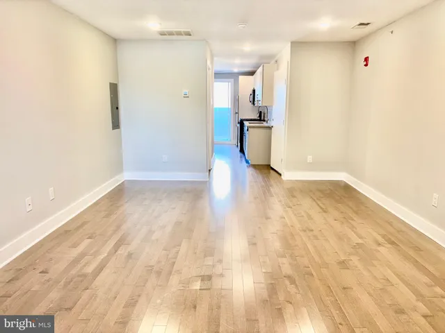 a view of a big room with wooden floor and a kitchen
