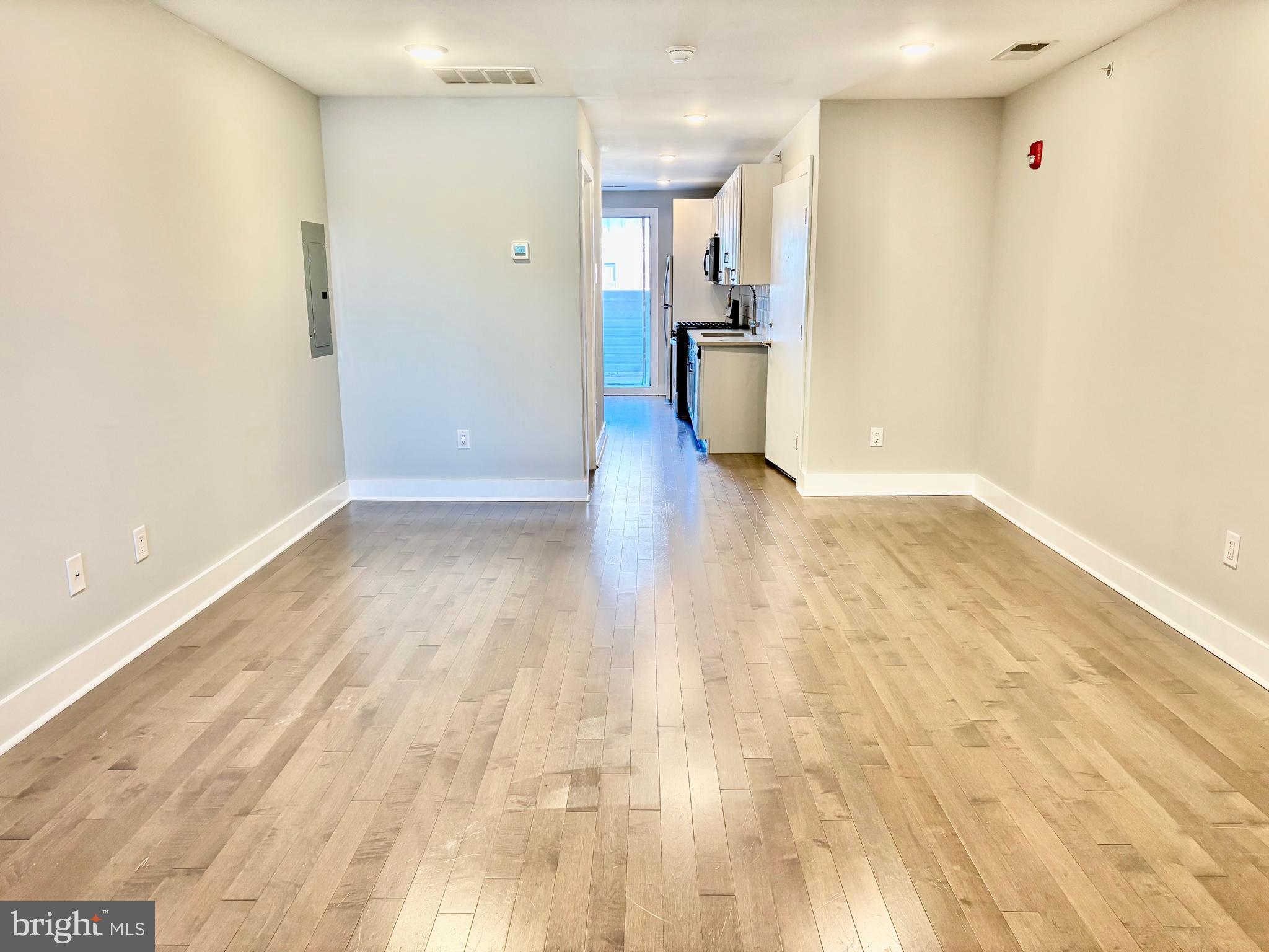 5334-36 Cedar Avenue, Unit 7G Philadelphia, PA 19143 - Photo 14 of 14 a view of a big room with wooden floor and a kitchen