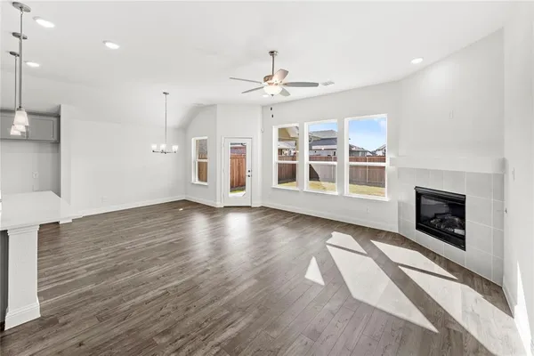an empty room with wooden floor fireplace and windows