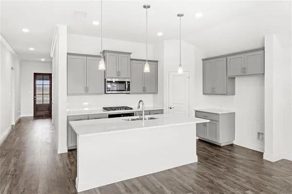 a large kitchen with stainless steel appliances kitchen island a refrigerator a sink dishwasher a stove and white cabinets with wooden floor