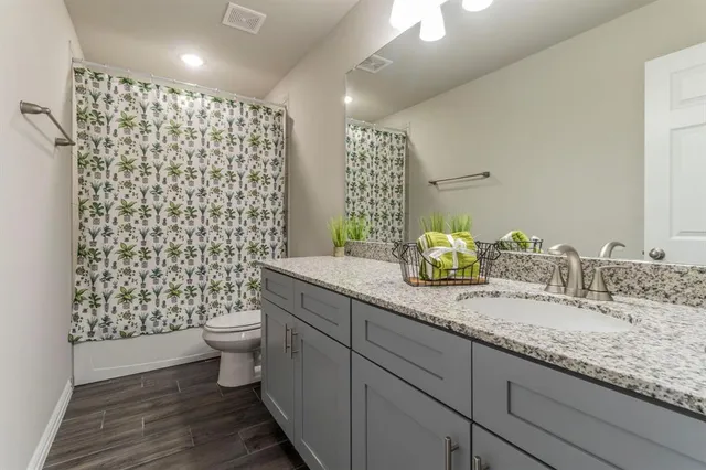 a bathroom with a granite countertop toilet a sink and a shower