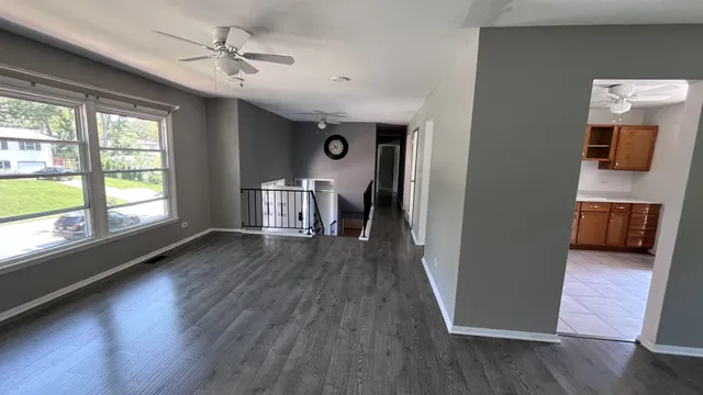 a view of a hallway with wooden floor and livingroom with furniture