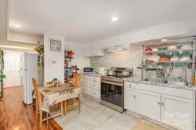 a kitchen with stainless steel appliances kitchen island granite countertop a refrigerator a sink dishwasher and white cabinets with wooden floor