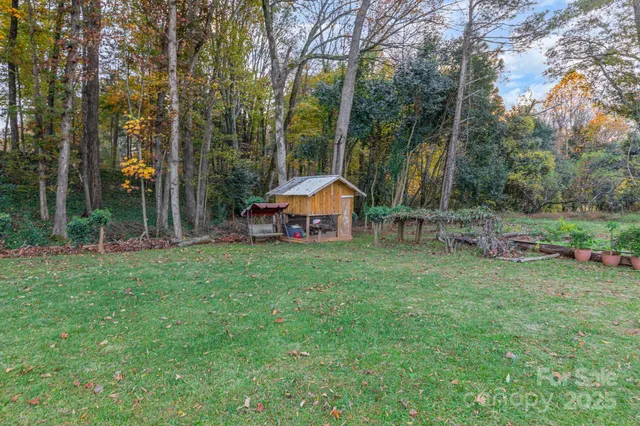 a backyard of a house with wooden fence and large trees
