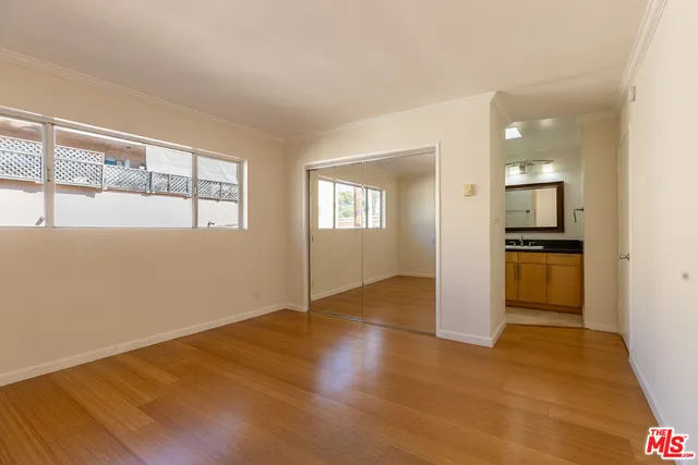 a view of empty room with wooden floor and kitchen