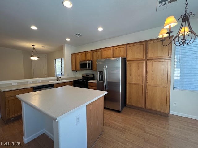 8229 Strawberry Spring Street Las Vegas, NV 89143 - Photo 9 of 40 Kitchen with decorative light fixtures, stainless steel appliances, brown cabinetry, light countertops, and a center island