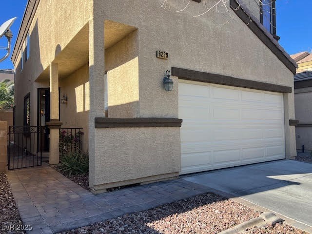 8229 Strawberry Spring Street Las Vegas, NV 89143 - Photo 3 of 40 View of property exterior featuring stucco siding, driveway, a garage, and a gate