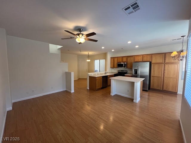 8229 Strawberry Spring Street Las Vegas, NV 89143 - Photo 40 of 40 Kitchen featuring open floor plan, a chandelier, brown cabinetry, black appliances, and a kitchen island