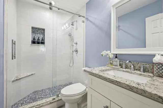 a bathroom with a granite countertop sink toilet and shower