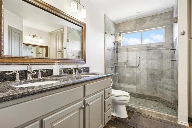 a bathroom with a granite countertop sink a toilet and a shower