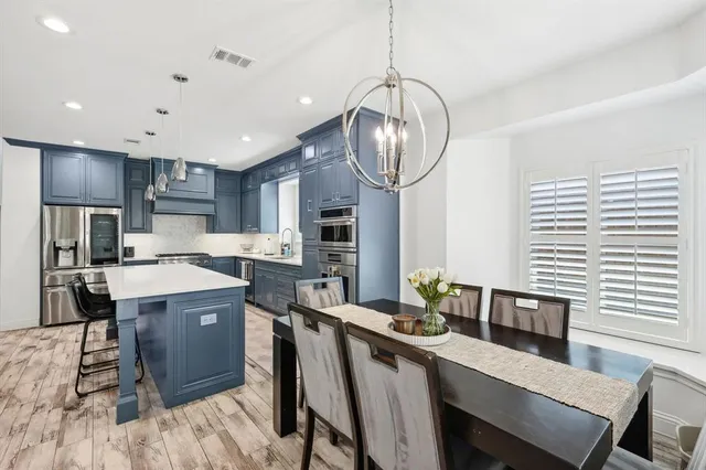 a kitchen with stainless steel appliances a table chairs and chandelier