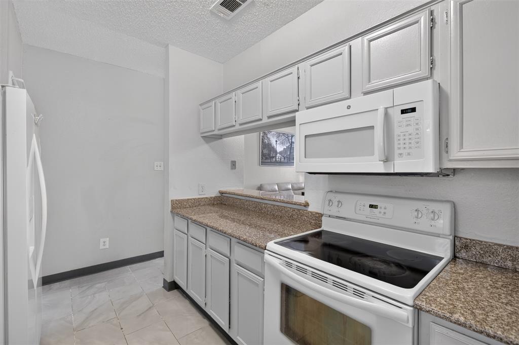 5550 Spring Valley Road, Unit G24 Dallas, TX 75254 - Photo 11 of 23 a kitchen with white cabinets and white appliances
