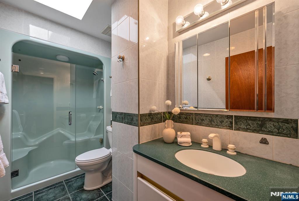 84 Bogerts Mill Road Harrington Park, NJ 07640 - Photo 31 of 47 a bathroom with a granite countertop sink toilet a mirror a bathtub and shower