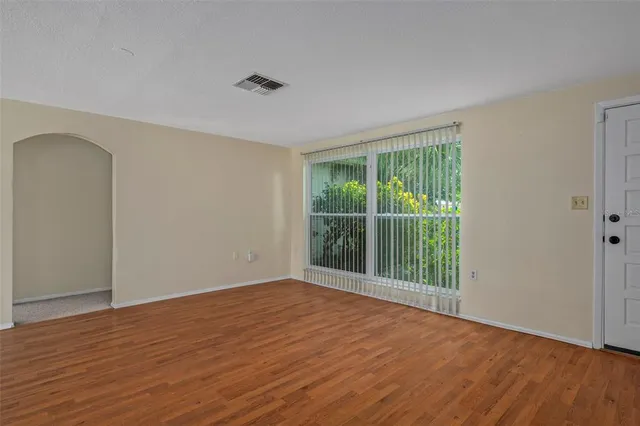 a view of an empty room with wooden floor and a window