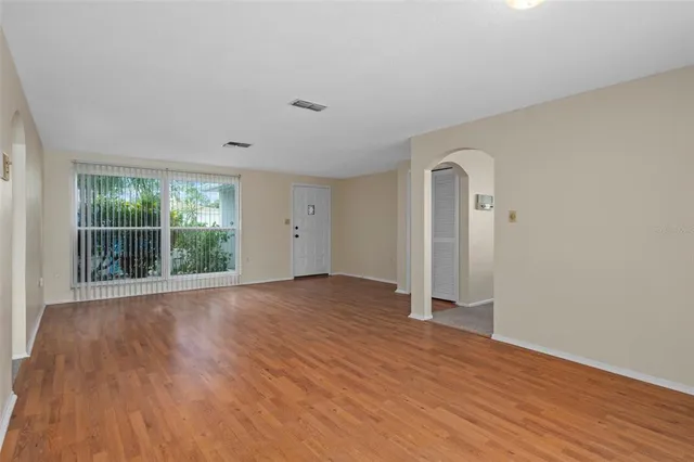 a view of an empty room with wooden floor and a window