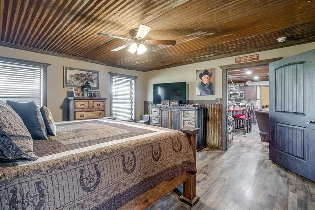 a spacious bedroom with a large bed a flat tv screen and dresser