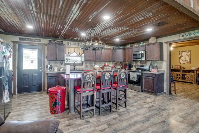 a kitchen with stainless steel appliances kitchen island granite countertop a table chairs sink and cabinets