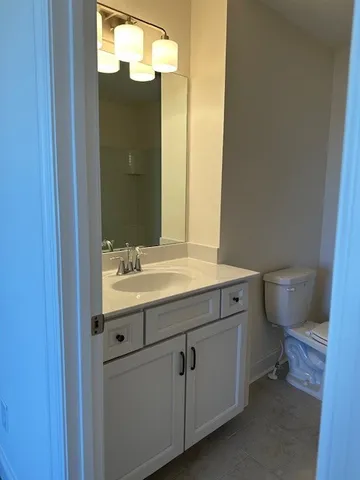 a bathroom with a granite countertop toilet sink and mirror
