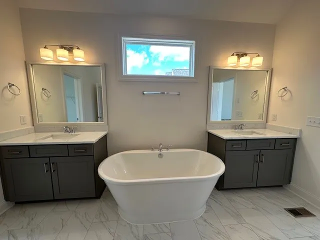 a bathroom with a bathtub a double vanity sink and a mirror