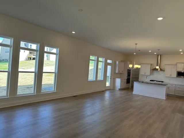 a view of an empty room with kitchen and window