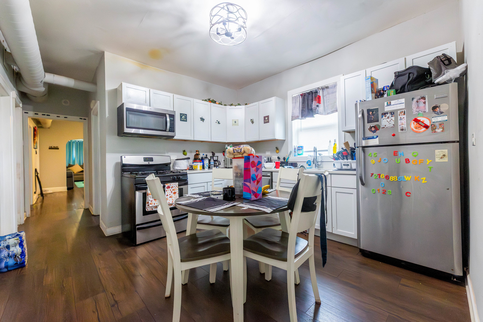 12258 South Normal Avenue Chicago, IL 60628 - Photo 15 of 21 a kitchen with stainless steel appliances a refrigerator a stove a dining table and chairs with wooden floor