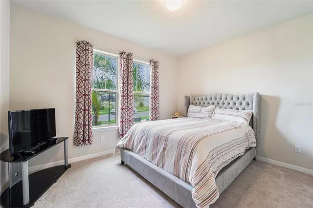 a spacious bedroom with a bed and a flat screen tv