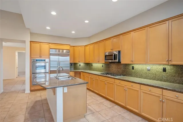 a kitchen with stainless steel appliances granite countertop a sink a stove and white cabinets with wooden floor