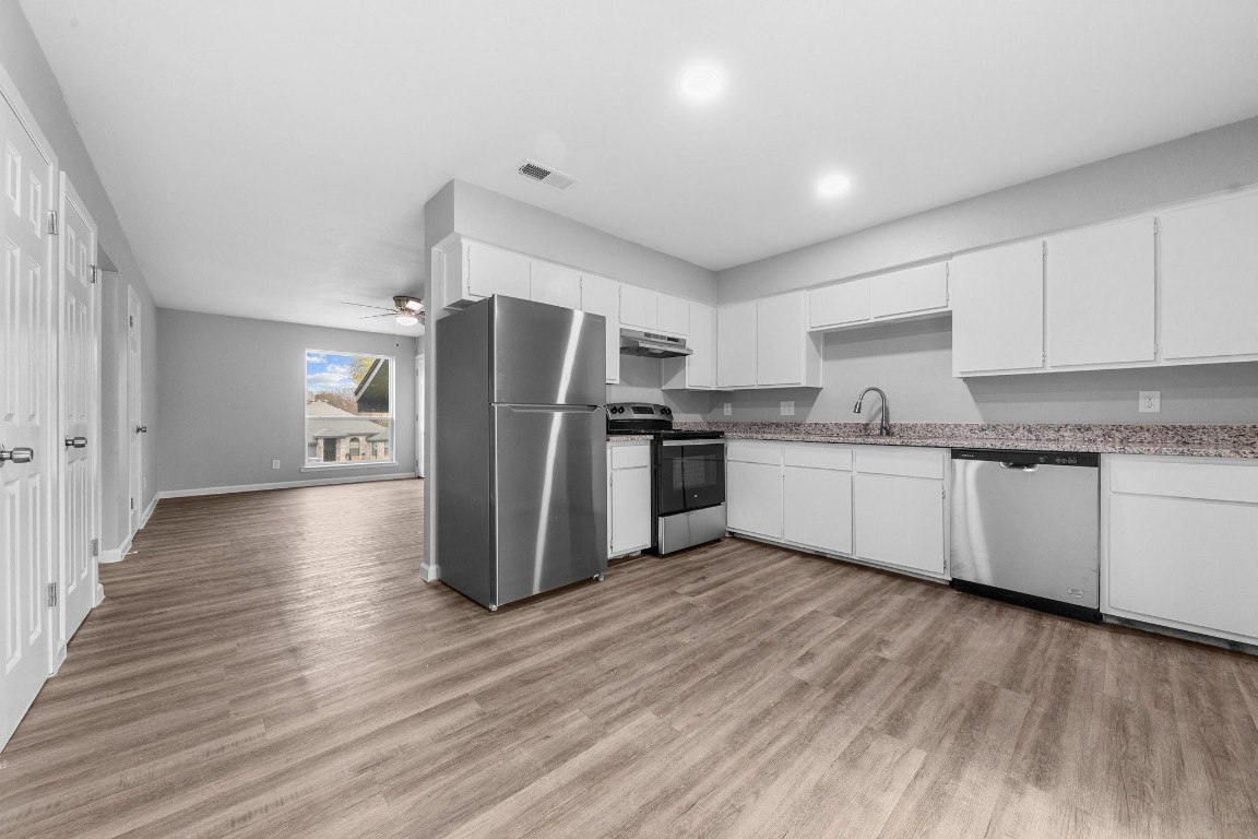 a kitchen with stainless steel appliances a refrigerator and wooden floor