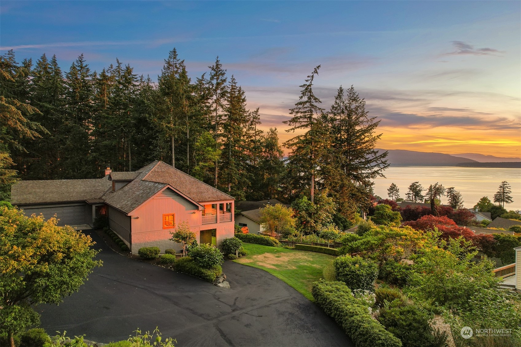 a front view of a house with a yard and mountain view in back