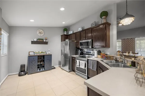 a kitchen with kitchen island granite countertop a stove top oven a sink dishwasher a dining table and chairs with wooden floor