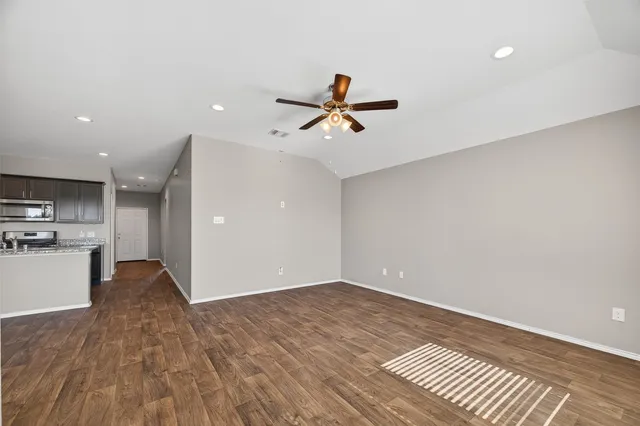 a view of an empty room with a window and wooden floor