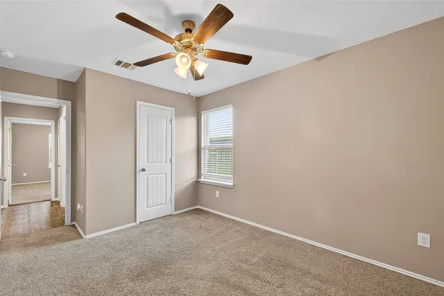 an empty room with a ceiling fan and a window