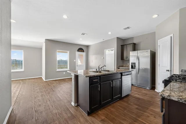 a kitchen with stainless steel appliances granite countertop a refrigerator and a sink