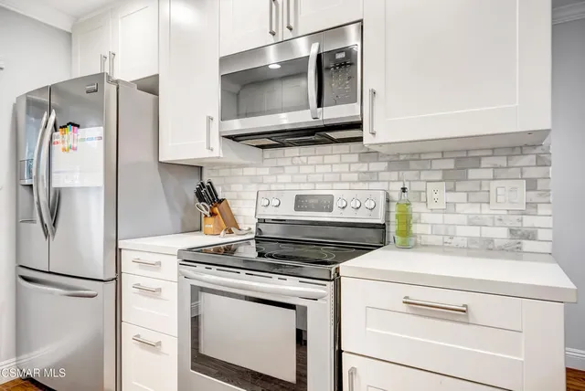a kitchen with stainless steel appliances white cabinets and a refrigerator