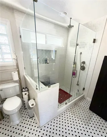 a bathroom with a sink a toilet a mirror and shower