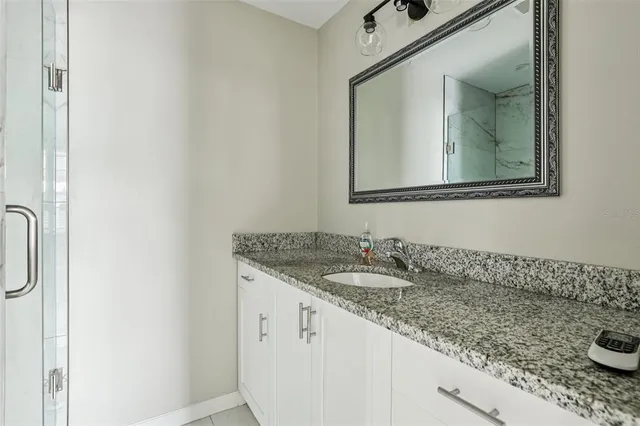 a bathroom with a granite countertop sink and a mirror