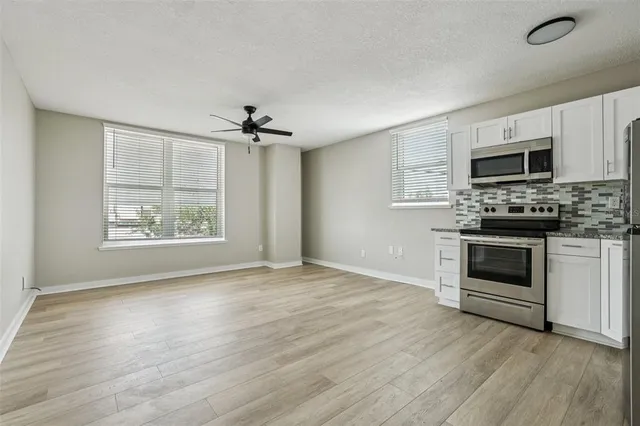 a view of kitchen with sink a microwave and cabinets