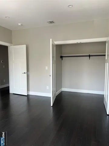 a view of an empty room with wooden floor and closet