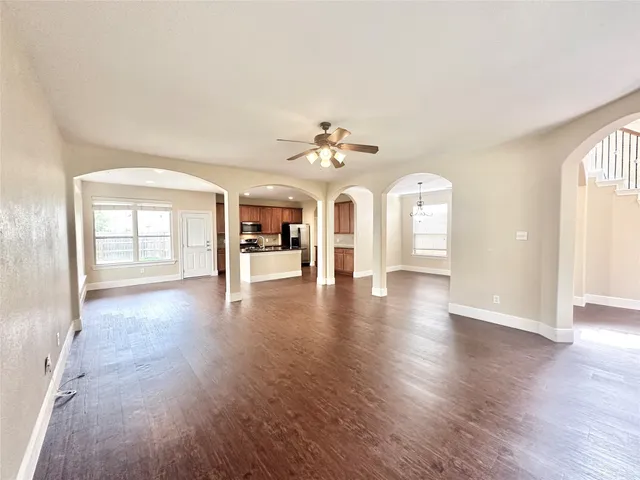 an empty room with wooden floor chandelier and windows