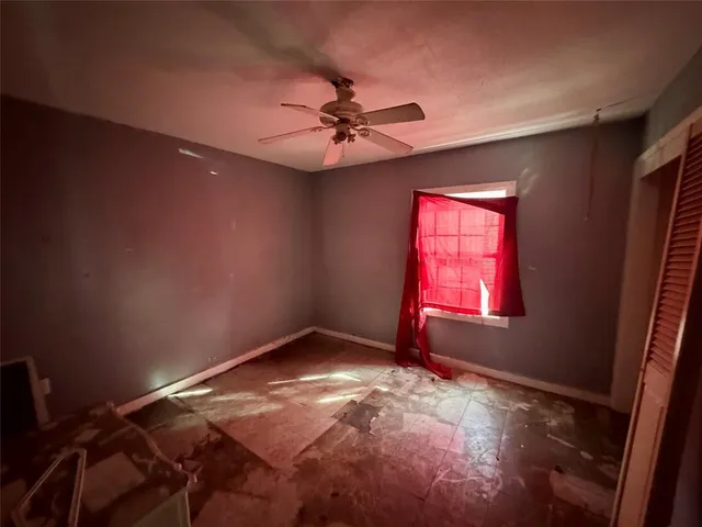 an empty room with windows and fan