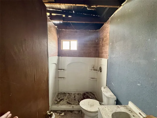 a bathroom with a granite countertop toilet a sink and shower