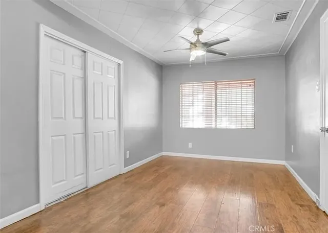 an empty room with wooden floor chandelier fan and windows