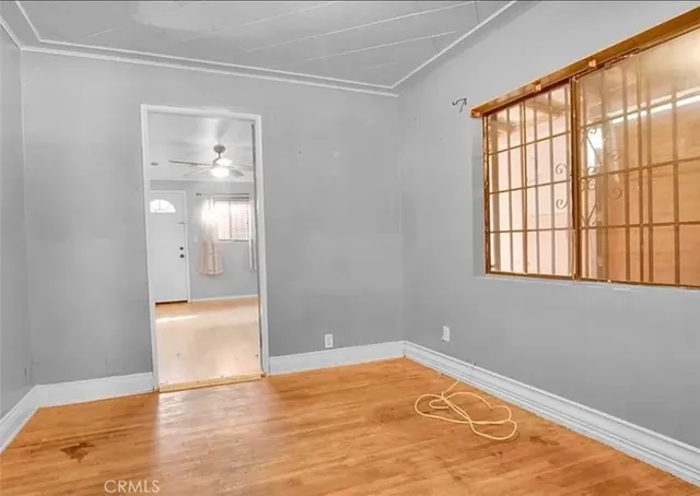 a view of empty room with wooden floor and fan